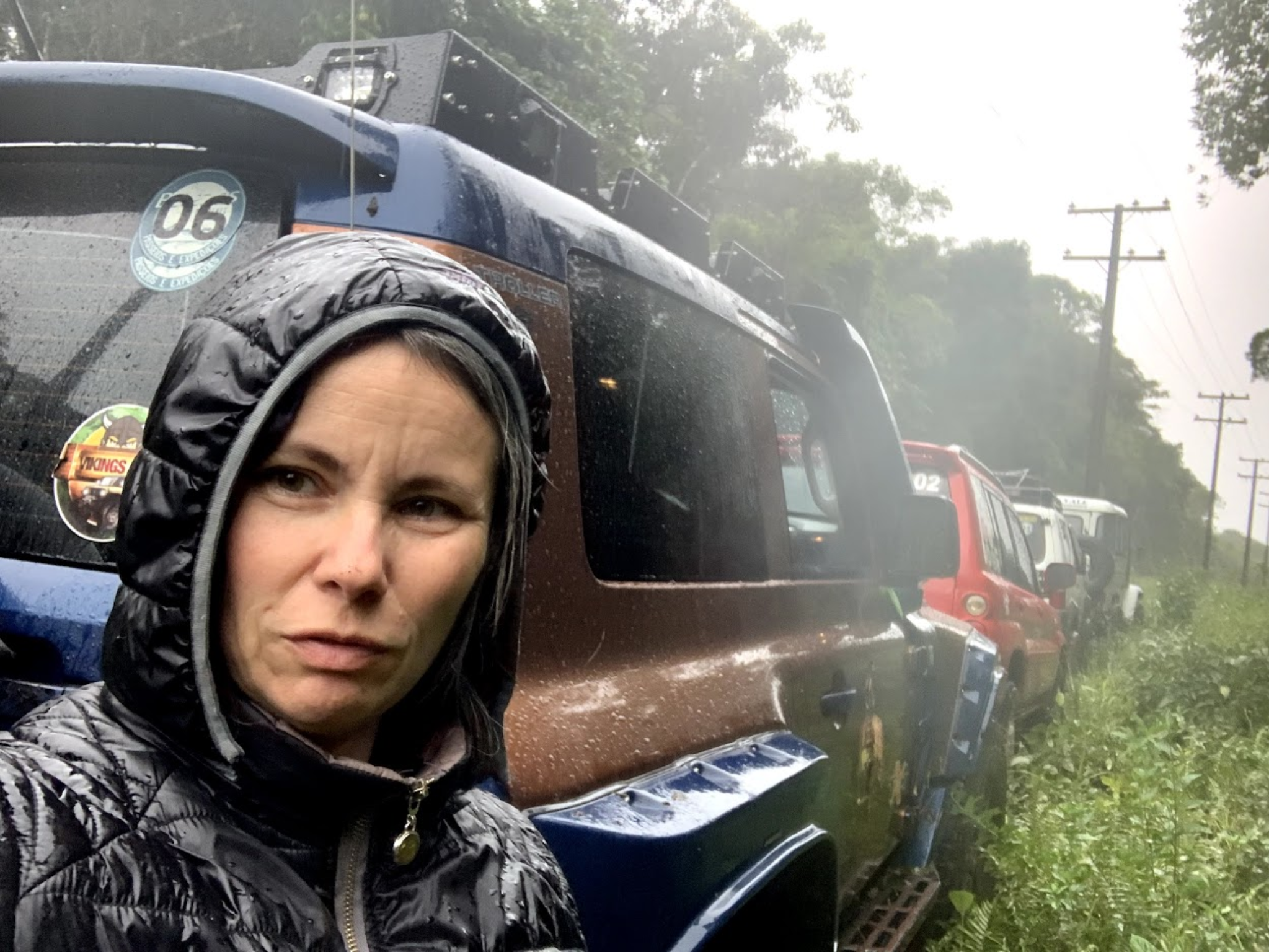 Pessoa em selfie ao lado do Troller TX4 em dia de chuva
