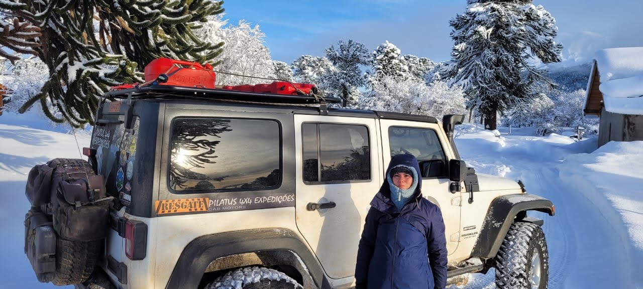 Jeep Wrangler em expedição na neve com pessoa ao lado